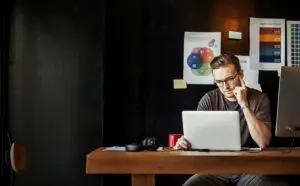 Homme concentré travaillant sur un ordinateur portable dans un bureau, entouré de graphiques et de documents de stratégie d'entreprise