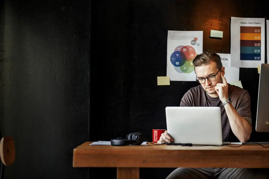 Homme concentré travaillant sur un ordinateur portable dans un bureau, entouré de graphiques et de documents de stratégie d'entreprise